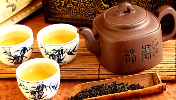 Китайский чайник и чашки с чаем на бамбуковой салфетке