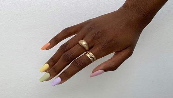 Разноцветные оттенки лака на ногтях, кольца на руке