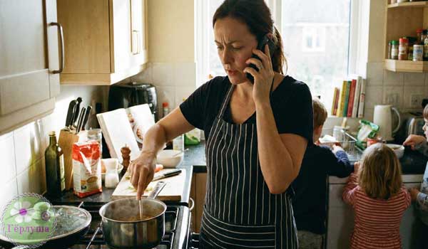 Женщина на кухне готовит и говорит по телефону